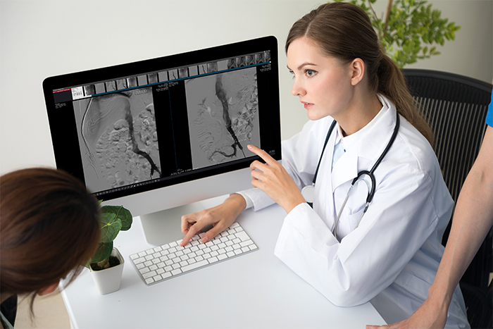A vascular doctor showing invasive exam images to a patient