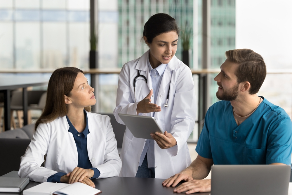 pacs system discussion between medical professionals in modern office with laptop and tablet