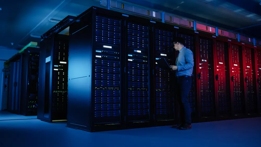 IT professional working in a data center with cloud servers, representing secure cloud-based disaster recovery and data backup infrastructure